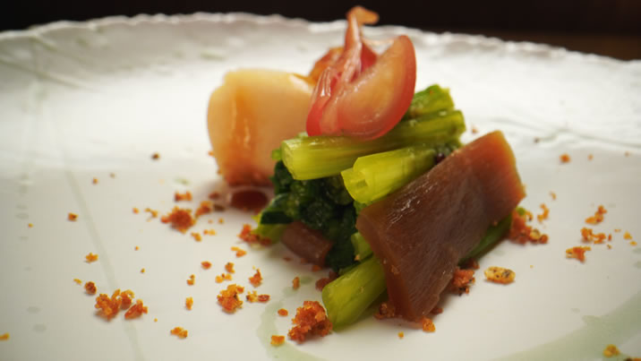 Hurley House - A gourmet dish artfully arranged on a white plate, featuring leafy green vegetables, thinly sliced reddish-pink radishes, translucent root vegetables, and scattered crunchy crumbs.