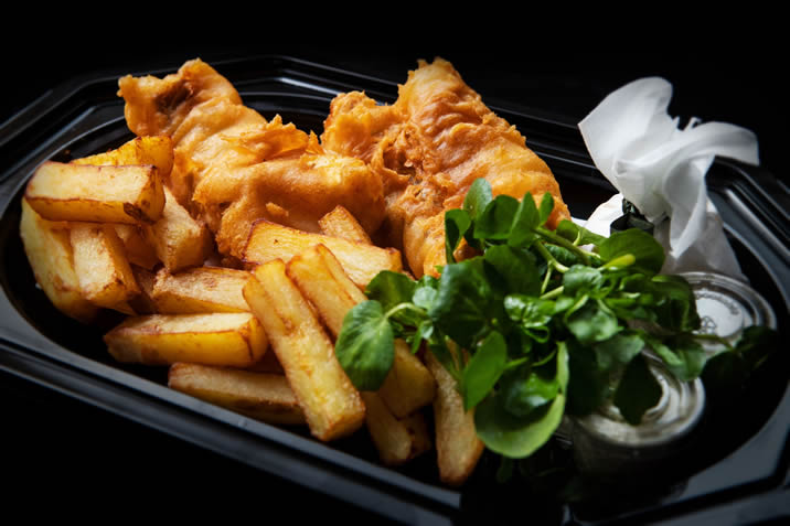 Hurley House - A black tray with golden battered fish, thick-cut fries, a side of green salad, a small container of tartar sauce, and a white napkin.